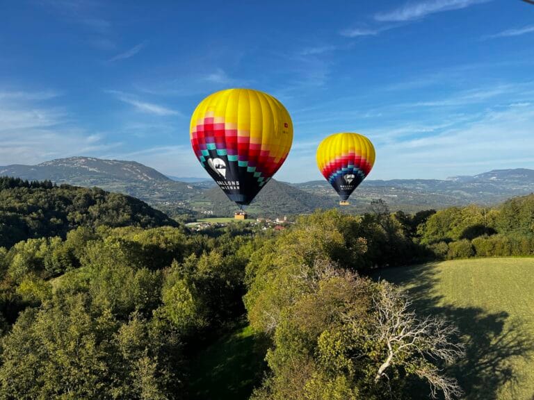 Deux montgolfières flottant au-dessus de la campagne et des forêts autour d’Annecy