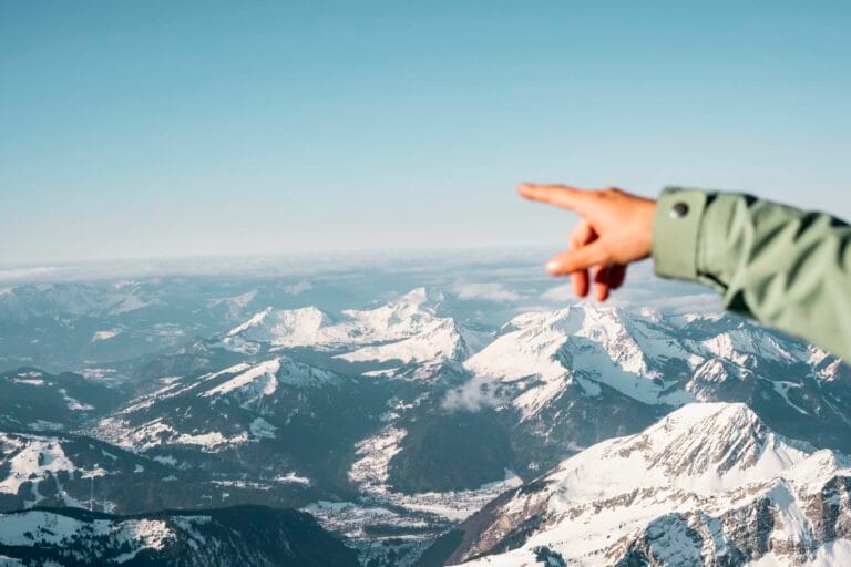 Main tendue depuis la nacelle d’une montgolfière vers les montagnes alpines